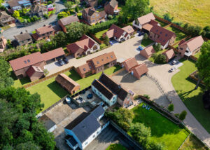 Aerial view of Dairy Farm development in Ormesby St Margaret, Norfolk, designed by leading Norfolk architects Paul Robinson Partnership. The image highlights six new builds, a barn conversion, and outbuildings, showcasing the firm's expertise in rural architecture and planning.