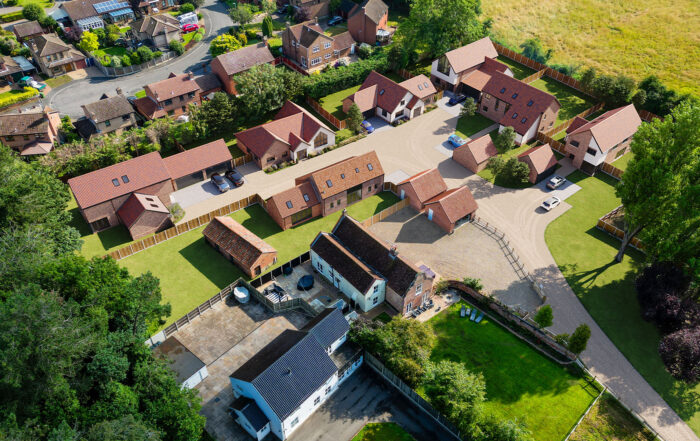 Aerial view of Dairy Farm development in Ormesby St Margaret, Norfolk, designed by leading Norfolk architects Paul Robinson Partnership. The image highlights six new builds, a barn conversion, and outbuildings, showcasing the firm's expertise in rural architecture and planning.