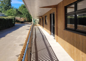 Timber-clad exterior of the Eccles Aurora School classroom block, designed by Norfolk architects Paul Robinson Partnership. Features include a covered walkway and contemporary design tailored to the needs of a non-mainstream educational environment.